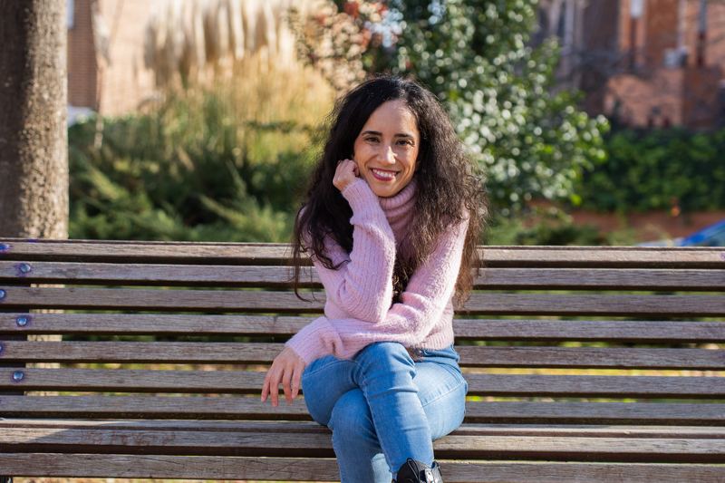 Retrato de Diana Texeira sentada en un banco de madera, sonriendo