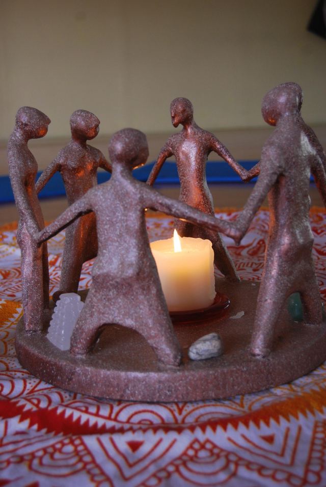 Figuras de barro cogidas de la mano en círculo alrededor de una vela